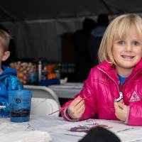 two kids coloring at alumni tent
